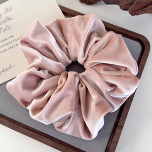 Detailed close-up of a pink velvet scrunchie with soft sheen on a tray