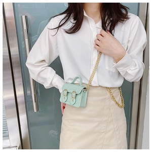 Detail of mint green mini satchel bag with gold chain strap on a female model