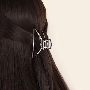 Close-up of a silver semi-circular metal hair claw clip worn on a modern hairstyle