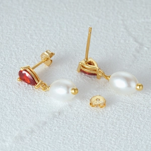Macro detail of S925 sterling silver earrings with pear-cut ruby and white pearl drop
