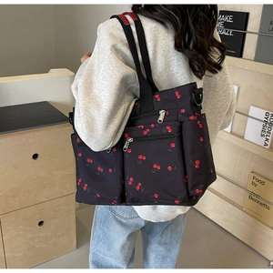 Deep blue tote bag with cherry print showing side view and zipper pocket detail