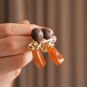 Close-up of vintage geometric earrings with dark wood tops and orange resin stones