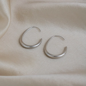 Detailed view of silver minimalist teardrop hoop earrings on champagne silk fabric