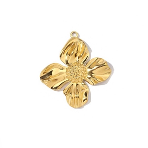 Detailed macro view of gold-plated flower clover pendant with textured petals and center beads
