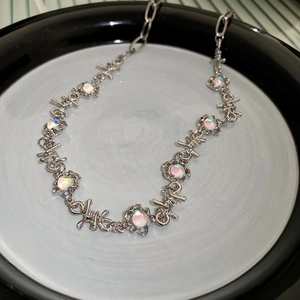 Detailed close-up of a silver thorn-link necklace featuring iridescent round cat eye stones