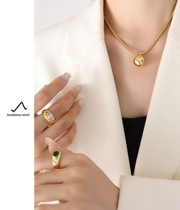 Detail of gold-plated snake chain necklace with ball pendant and vintage gemstone rings