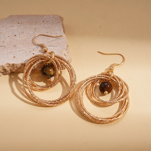 Geometric gold multilayer circle earrings with brown tiger eye stone on a stone prop