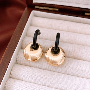 Close-up of geometric gold and black earrings in a luxury wooden jewelry gift box