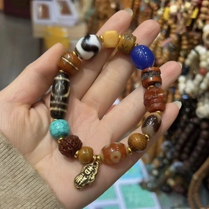 Close-up of vintage ethnic bracelet featuring agate beads and engraved auspicious metal charm