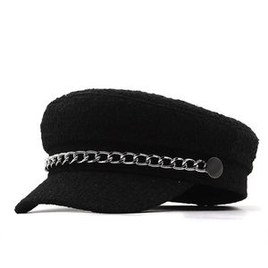 Close-up of black tweed newsboy hat featuring a silver chain and textured fabric detail