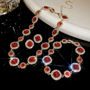 Makroaufnahme von Goldschmuck-Set mit roten ovalen Edelsteinen und glitzernden Zirkonia