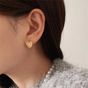 Elegant gold heart stud earrings with cubic zirconia stone worn by a model in profile