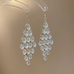 Detail of long tassel drop earrings with clear faceted beads and golden metal rings