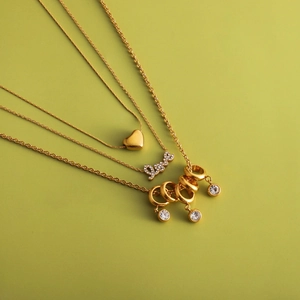 Détails de trois colliers plaqués or 18 carats avec pendentifs cœur, Love et oxydes de zirconium