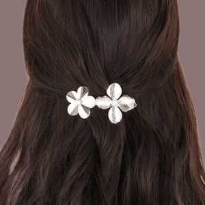 Detail view of silver floral hair clip with twin flower design on dark hair