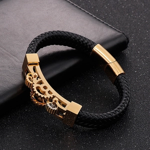 Detail of black braided leather men's bracelet with gold gear-style mechanical accents