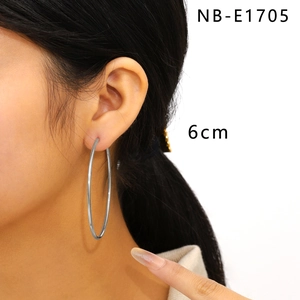 Close-up of 6cm large polished silver hoop earrings worn by model showing actual size