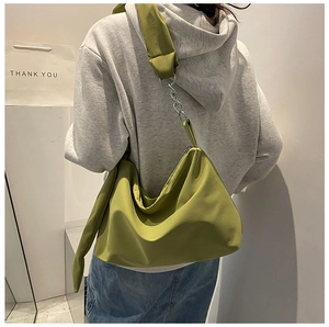 Detail of avocado green nylon crossbody bag with fabric strap and silver chain accent