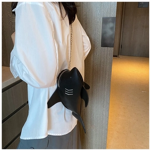 Detail showing a creative black shark-shaped crossbody bag with a sleek metal chain strap
