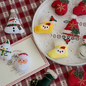 Flat lay of embroidered Christmas plush charms including snowman, Santa and socks