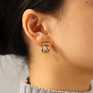Boucles d'oreilles de luxe en acier doré avec zircon rectangulaire portées par un modèle