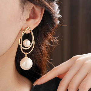 Close-up of irregular gold earrings with pearls worn by a model for a luxury fashion look