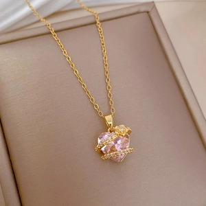 Macro view of golden heart necklace with pink gemstone and floral accents