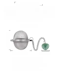 Macro detail of stainless steel mesh tea infuser with heart-shaped green crystal pendant