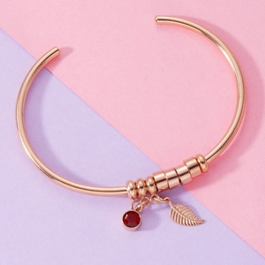 Rose gold stainless steel bracelet featuring a red birthstone and leaf charm detail