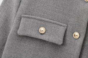 Detailed macro shot of grey tweed fabric texture and ornate gold embossed buttons