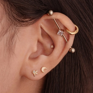 Detail of S925 sterling silver opal piercing set featuring moon and petal gold studs