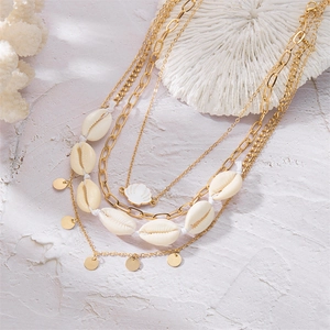 Detail of layered gold necklace with white natural shells and starfish on coral background
