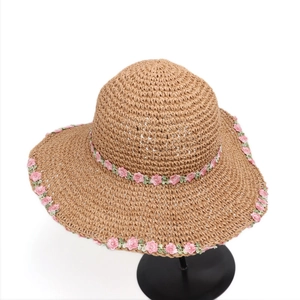 Detailed embroidery of pink lace flowers on a natural straw summer sun hat