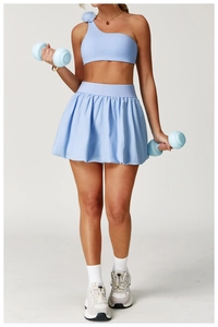 Detail of light blue tennis skirt and one-shoulder sports bra with floral accent