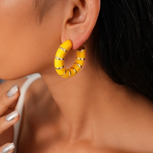 Close-up of yellow C-shaped hoop earring with gold metal stripes on model