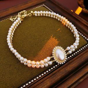 Detail of double-layer pearl necklace with a gold oval diamond pendant on a brown tray