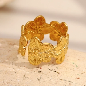 Macro shot of 18K gold plated flower ring on a beige textured pedestal for premium detail
