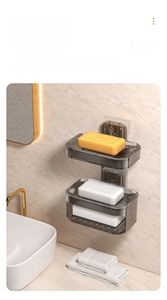 Detail view of a double-layer smoke grey wall-mounted soap holder with drainage