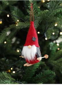Detail of a skiing Christmas gnome ornament with red hat and wooden skis on a tree