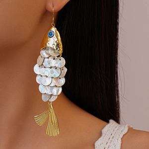 Detailed close-up of fish-shaped earrings with iridescent shell scales and golden metal