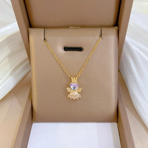 Gros plan du pendentif ange doré avec pierre précieuse dans une boîte à bijoux brune
