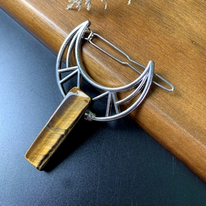 Macro shot of silver crescent moon hair clip with natural tiger eye stone and hair comb
