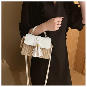 Close-up of straw woven crossbody bag with white PU leather flap and tassel detail