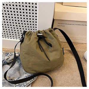 Detail of army green nylon bucket bag with adjustable black strap and drawstring closure