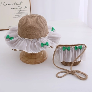 Detail of children's straw hat and matching bag with lace trim and green ribbon bow
