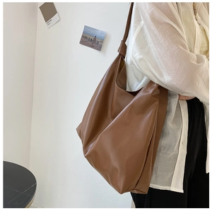Side view of a large brown leather tote bag showing its sleek profile and strap