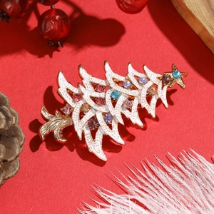 Detail of Christmas tree brooch with white enamel, rhinestones and festive red background