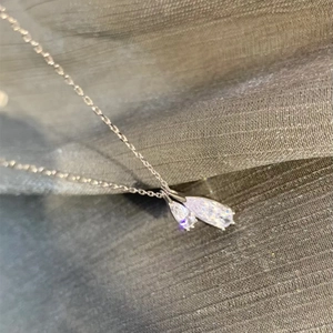 Detail shot of elegant double teardrop silver pendant with sparkling zircon on dark cloth