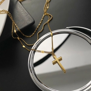 Three-layer titanium steel cross necklace in gold finish on reflective surface