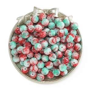 Close-up of red and green marbled round beads in a decorative silver display tray
